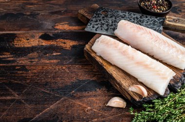 Çiğ morina fileto bifteği ve kasap satırı. Koyu ahşap arka plan. Üst Manzara. Boşluğu kopyala