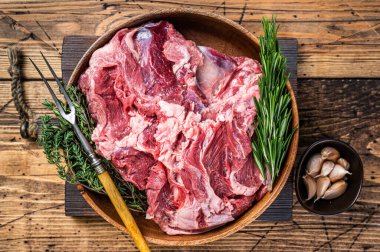 Kemiksiz çiğ koyun eti, ahşap tabakta, otlu omuz eti. Ahşap arka plan. Üst görünüm