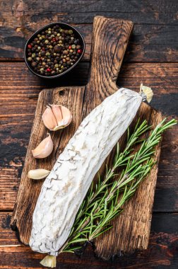 İspanyol kurutulmuş salçalı salamı kesme tahtasında. Koyu ahşap arka plan. Üst görünüm