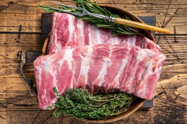 Et çatalıyla ahşap tabakta çiğ domuz pirzolası. Ahşap arka plan. Üst görünüm