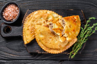 Cheburek etli börek ve şifalı otlar. Siyah ahşap arka plan. Üst görünüm