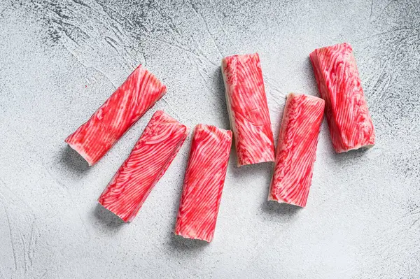 Yengeç surimi mutfak masasına yapışıyor. Beyaz arka plan. Üst görünüm