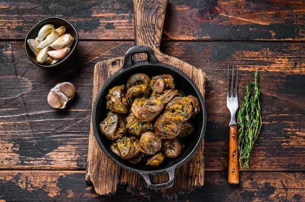 Cooked turkey hearts offals with herbs. Dark wooden background. Top view