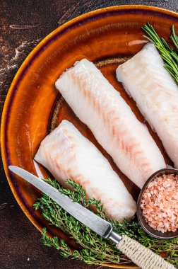 Çiğ Haddock fileto fileto balığı kekik ve tuzlu kırsal tabakta. Karanlık arka plan. Üst görünüm