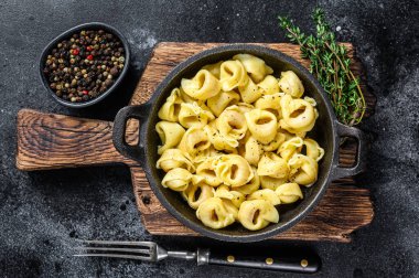 Tavada peynir soslu İtalyan tortellini makarnası. Siyah arka plan. Üst görünüm