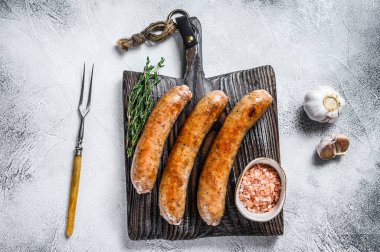 Ahşap kesme tahtasının üzerinde baharat ve otlarla kızartılmış sosisler. Üst Manzara. Beyaz arkaplan