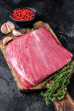 Tahta kesme tahtasının üzerinde çiğ kanat ya da biftek. Siyah arka plan. Üst görünüm