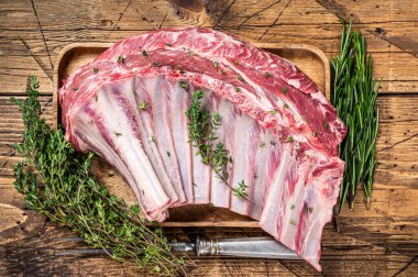 Ahşap tepside otlu kuzu pirzola rafı. Ahşap arka plan. Üst görünüm