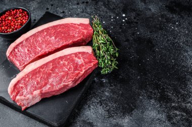 Çiğ biftek ya da mermer tahtada sığır eti bifteği. Siyah arka plan. Üst Manzara. Boşluğu kopyala