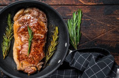 Tavada ızgara çizgili biftek ve otlar. Koyu ahşap arka plan. Üst Manzara. Boşluğu kopyala