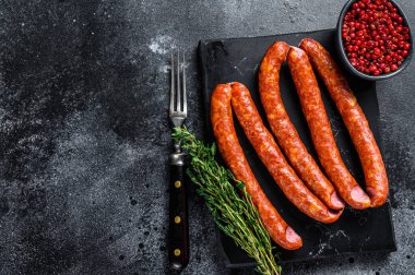 Mermer bir tahtanın üzerinde füme sosis. Siyah arka plan. Üst Manzara. Boşluğu kopyala