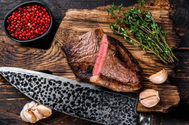 Ahşap bir tahtanın üzerinde kızarmış popo şapkası ya da Brezilya usulü picanha bifteği. Koyu ahşap arka plan. Üst görünüm