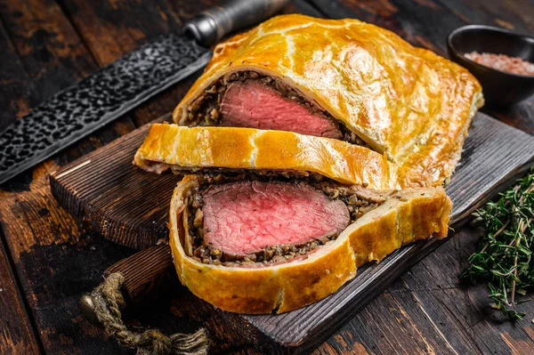 Homemade Beef Wellington puff pie with tenderloin meat on a cutting board. Dark wooden background. Top view — Stock Photo, Image