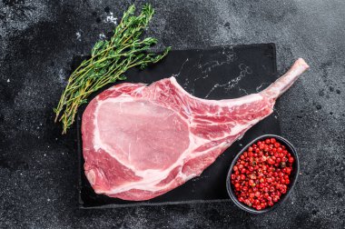 Misket tahtasında çiğ, taze, domuz pirzolası bifteği. Siyah arka plan. Üst görünüm