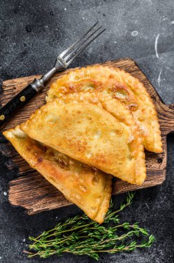 Et ve bitkilerle yağlı cheburekler içinde kızartılmış, geleneksel Kafkas mutfağı. Siyah arka plan. Üst görünüm