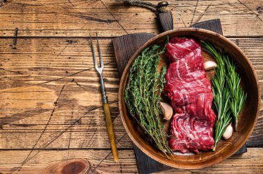 Tahta tabakta çiğ, etekli biftek ve şifalı otlar. Ahşap arka plan. Üst Manzara. Boşluğu kopyala