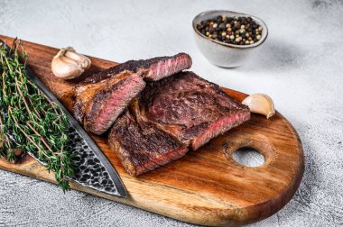 Ahşap kesme tahtasının üzerinde ızgara biftek. Beyaz arka plan. Üst görünüm