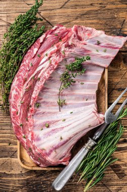 Ahşap tepside otlu kuzu pirzola rafı. Ahşap arka plan. Üst görünüm