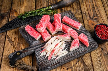 Tahta kesme tahtasında dilimlenmiş yengeç çubukları ve et. Ahşap arka plan. Üst görünüm