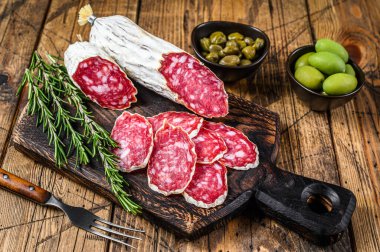 Tahta kesme tahtasının üzerinde ince dilimlenmiş salam salçamı. Ahşap arka plan. Üst görünüm