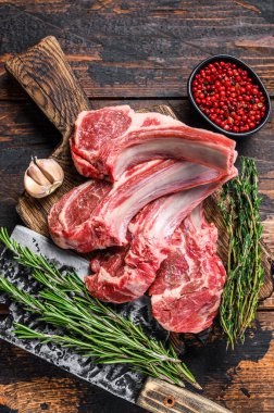 Kasap kesim tahtasında kuzu pirzola bifteği. Koyu ahşap arka plan. Üst görünüm