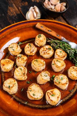 Tabakta tereyağlı baharat soslu kızarmış istiridye. Koyu ahşap arka plan. Üst görünüm