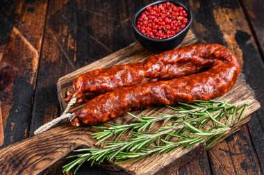 Chorizo domuz eti kurutulmuş et sosisi ahşap bir kesme tahtasında. Koyu ahşap arka plan. Üst görünüm