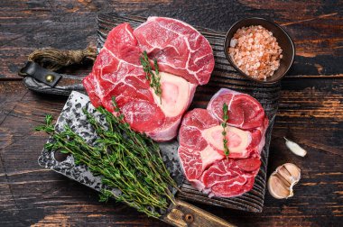 Çiğ dana incik bifteği, osso buco, İtalyan ossobuco pişirme. Karanlık ahşap arka plan. Üst görünüm