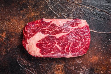 Kasap masasında pişirmek için hazırlanmış çiğ biftek bifteği. Karanlık arka plan. Üst görünüm