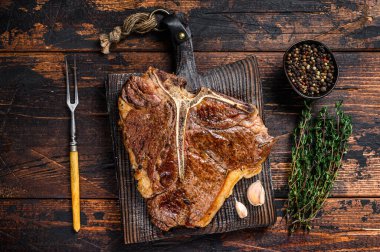 Biftek ya da ahşap bir kesme tahtasının üzerinde biftek. Koyu ahşap arka plan. Üst görünüm