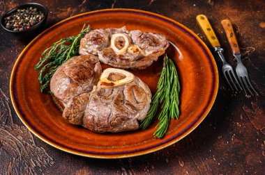 Kemikte pişmiş et, Osso Buco dana inciği, İtalyan ossobuco bifteği. Koyu ahşap arka plan. Üst görünüm