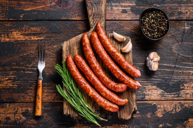 Taze aromatik otlar ve baharatlarla birlikte sıcak füme sosis. Koyu ahşap arka plan. Üst görünüm