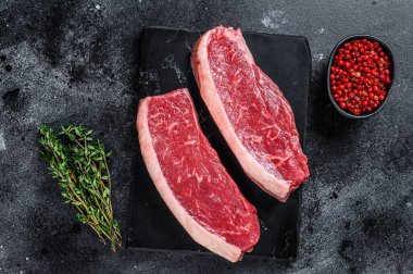 Çiğ biftek ya da mermer tahtada sığır eti bifteği. Siyah arka plan. Üst görünüm