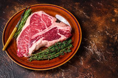 Çiğ biftek bifteği ve tabakta otlar. Karanlık arka plan. Üst Manzara. Boşluğu kopyala