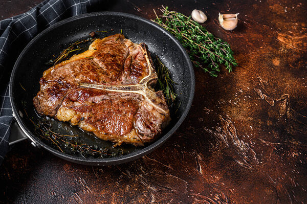 BBQ Grilled t-bone beef meat Steak with herbs on a plate. Dark background. Top view. Copy space