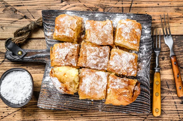 Pastelería griega Bougatsa con pasta de filo y crema de natillas de sémola. Fondo de madera. Vista superior —  Fotos de Stock