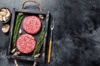 Hamburger için çiğ et köftesi, kıyma ve ahşap bir tahtanın üzerinde bulunan otlardan. Siyah arka plan. Üst Manzara. Boşluğu kopyala