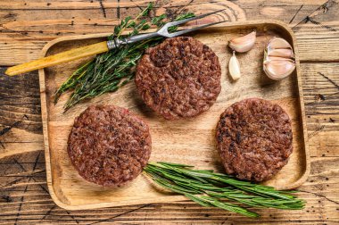 Barbekü ızgara biftek köfteleri, ahşap tepside kıyma. Ahşap arka plan. Üst görünüm