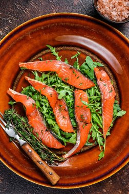 Roka salatası ve füme somon filetosu. Karanlık arka plan. Üst görünüm