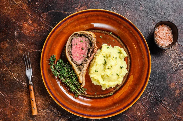 Beef Wellington pastry with mushed potato on a rustic plate. Dark background. Top view — Stock Photo, Image