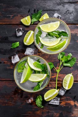 Taze limonata mojito. Naneli mojito, limon ve buz. Siyah ahşap arka plan. Üst görünüm