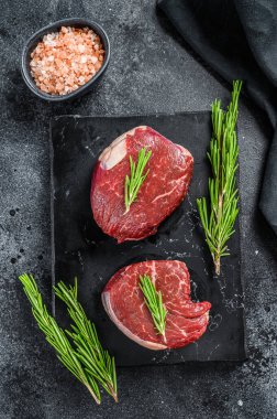 Filetodan kesilmiş iki parça ince biftek. Siyah arka plan. Üst görünüm.