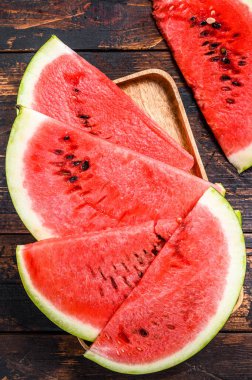 Bir yığın taze kırmızı dilimlenmiş karpuz. Karanlık ahşap arka plan. Üst görünüm