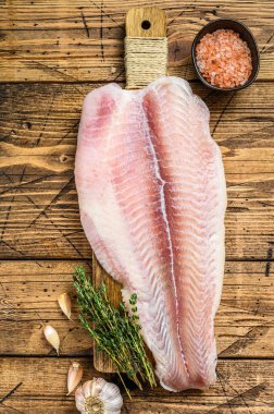 Kesme tahtasındaki çiğ pangasius balığı filetosu. Ahşap arka plan. Üst görünüm
