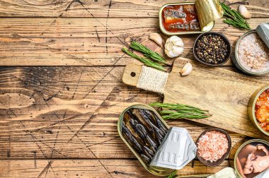 Açılmış kutular saury, somon, sprat, sardalya, kalamar ve ton balığıyla korunur. Ahşap arka plan. Üst Manzara. Boşluğu kopyala