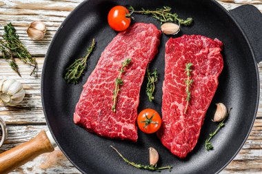 Denver bifteği ve otlu bir tavada mermer biftek. Organik et. Beyaz ahşap arka plan. Üst görünüm