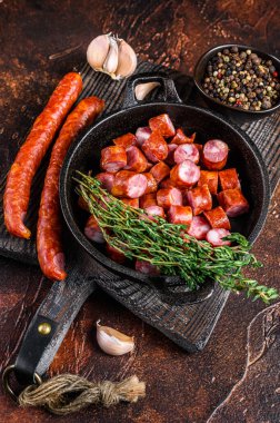 Dilimlenmiş sıcak füme sosis, aromatik otlar ve baharatlar. Karanlık arka plan. Üst görünüm