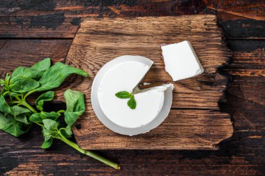 Tahta tahtada taze Ricotta krem peyniri ve fesleğen. Koyu ahşap arka plan. Üst görünüm