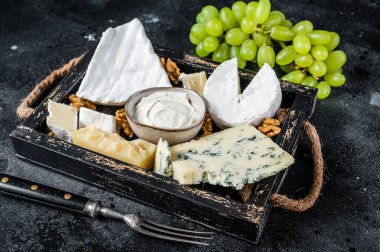 Peynirli, peynirli, peynirli, peynirli, peynirli, rokforlu, parmesanlı, peynirli, üzümlü ve fındıklı. Siyah arka plan. Üst görünüm