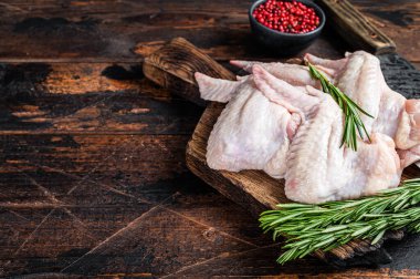 Et satırıyla kasap tahtasında pişmemiş çiğ tavuk kanadı. Karanlık ahşap arka plan. Üst Manzara. Boşluğu kopyala